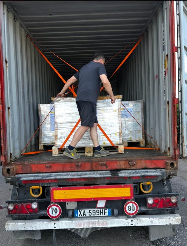 Worker loading truck with strapped cargo