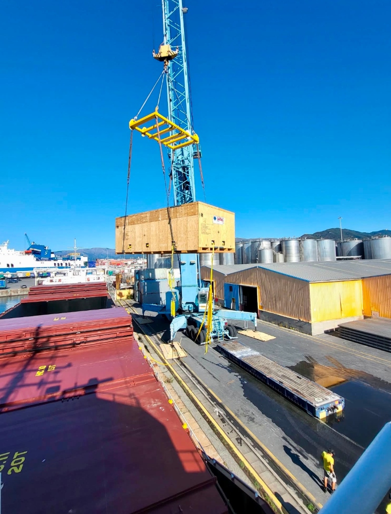 Port crane lifting SIMIC heavy industrial crate onto cargo ship