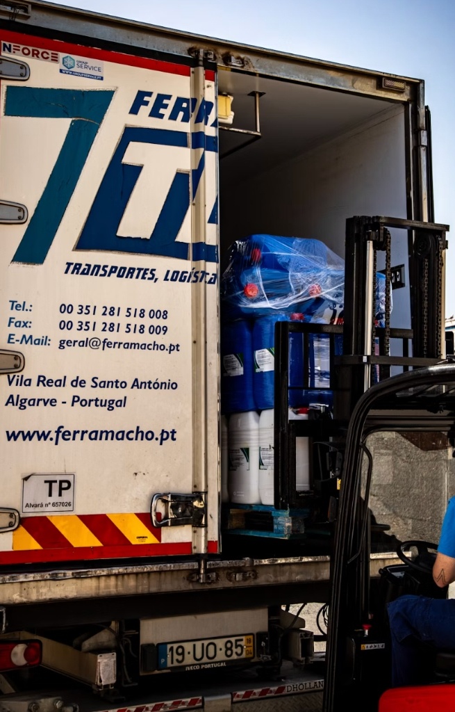 Forklift loading chemical drums into refrigerated cargo truck